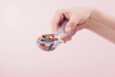 女性用汤匙拿着药丸的局部视图隔离在粉红色上