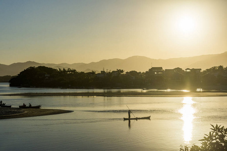 巴西南部圣卡塔琳娜州瓜达多姆博海滩日落时分，一艘小船在马德拉河边行驶