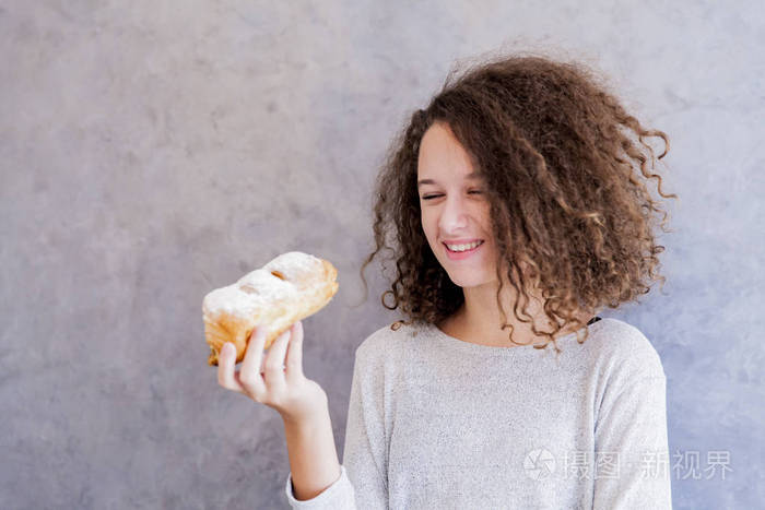 卷曲的头发少女吃羊角面包