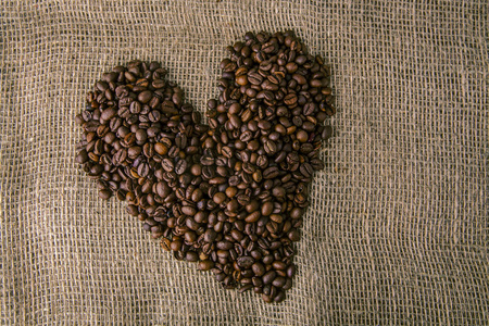 咖啡豆在心形的背景上被解雇了。 用咖啡豆做成的心形咖啡架