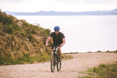 主题旅游和山地自行车骑自行车。人骑在岩石, 岩石的道路上, 在地中海的背景, 在西班牙的 kosta 的岸边, 头盔和运动服