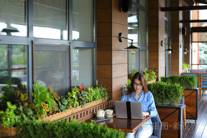 美丽的女孩在咖啡馆里用手提电脑浏览