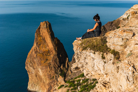长胡子的嬉皮士游客坐在山附近高山的悬崖边爱的夫妇坐在海边的悬崖边