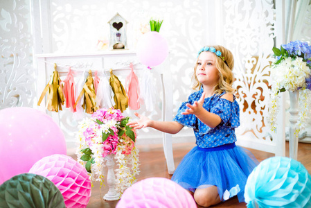 一幅美丽的小女孩的画像在一个装饰着许多彩色气球的工作室里笑