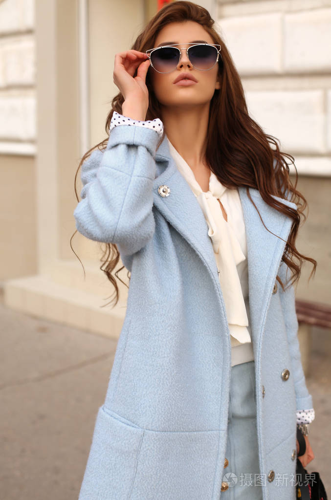 美丽的女孩穿着优雅的衣服走在街上