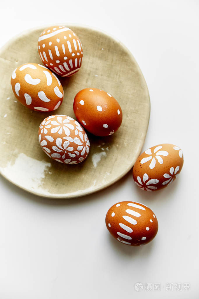 带有白色彩绘鸡蛋的盘子与白色背景复活节假期概念隔离的各种图案
