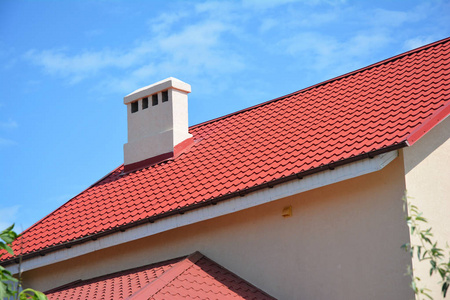 美丽的红色金属屋顶，屋顶排水沟筋膜通风和烟囱。 房屋屋顶建筑。