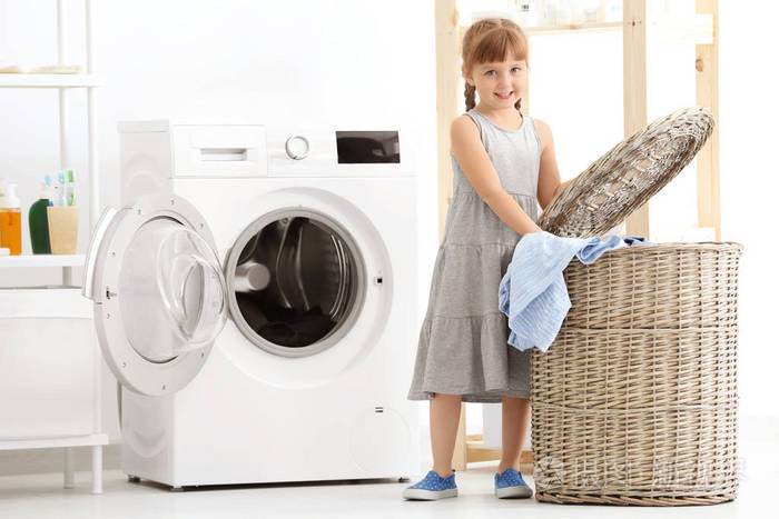 可爱的小女孩在室内洗衣服