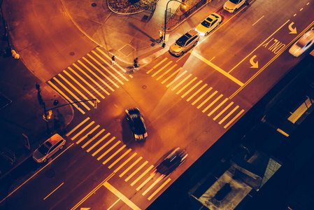 汽车和人在道路交叉口，夜间在城市街道上有信号灯和人行横道