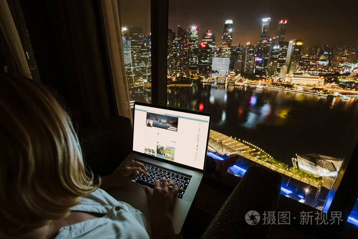 妇女自由职业者的工作是使用笔记本电脑在家庭办公室晚上从窗口鸟瞰