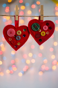 红色感觉心工艺品装饰珠子和按钮在彩色背景与灯。 情人节装饰。