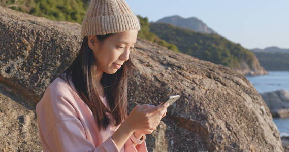 有海景背景的女人用手机