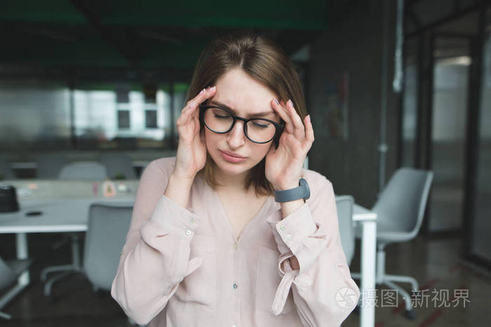 一位女白领头疼那女孩头疼得把手举到头上办公室工作中的主要痛苦