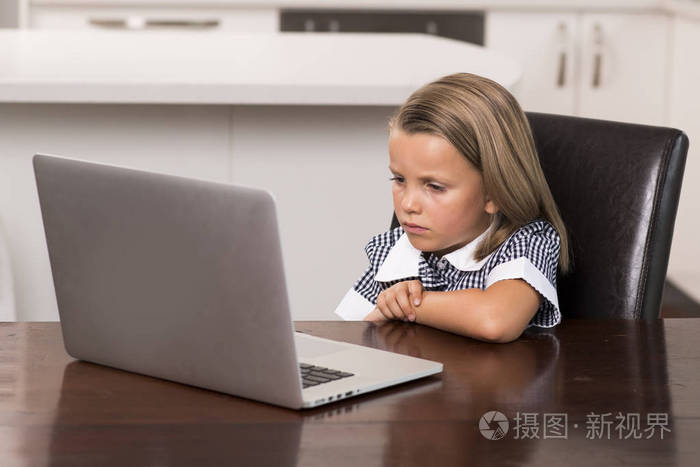 小女孩6到8岁坐在家里厨房享受与笔记本电脑集中观看网络卡通电影