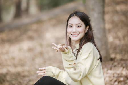 美丽的亚洲女人微笑着快乐的女孩，在公园的户外穿着温暖的衣服，冬天和秋天的肖像。