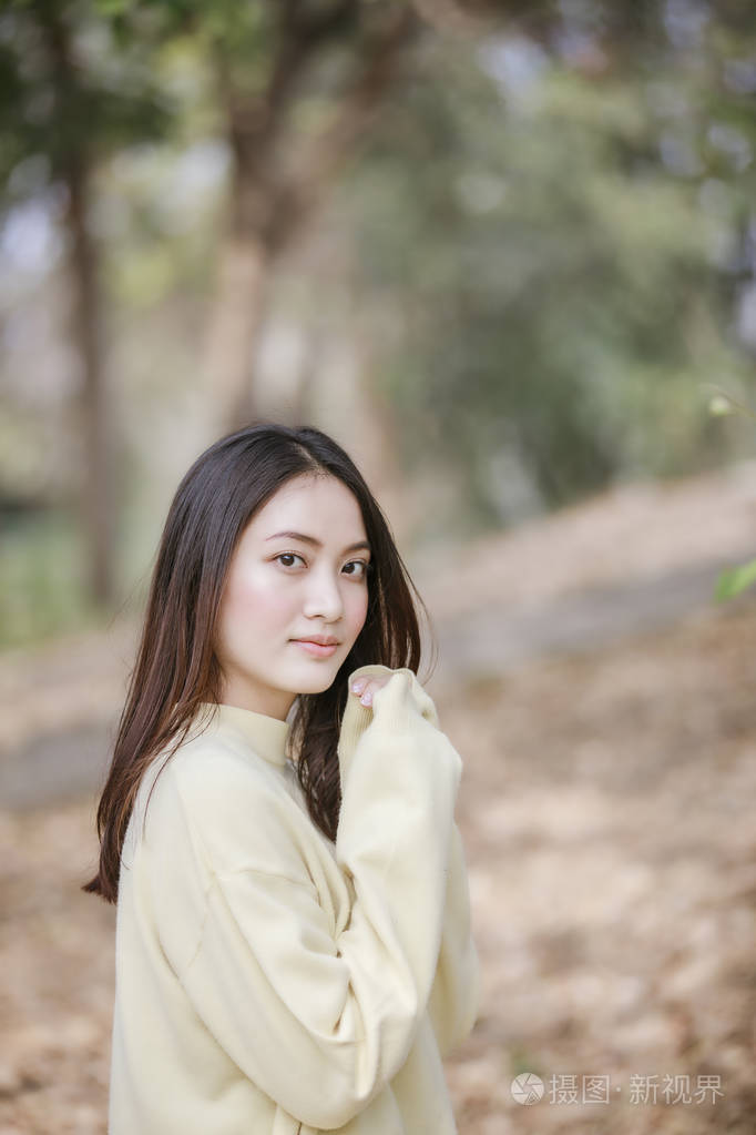 美丽的亚洲女人微笑着快乐的女孩,在公园的户外穿着温暖的衣服,冬天和