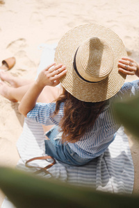 帽子后面的女孩坐在沙滩上