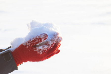 红手套中的妇女之手在她们的手掌上放着雪。冬季会议