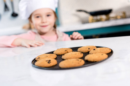近距离观看美味的甜饼干和孩子在厨师帽后面。