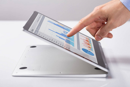 s Finger Pointing At The Business Graph On The Hybrid Laptop