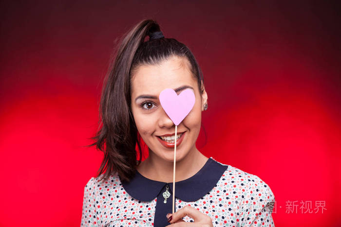女人用粉红色的papper的心遮住她的眼睛