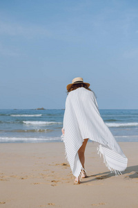 女孩在一顶帽子漫步沿海滩
