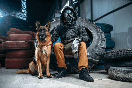 跟踪者戴着防毒面具，狗朋友在末日后的世界。 后世界末日生活方式废墟末日概念