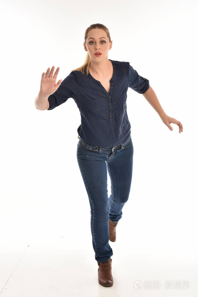 穿着简单的蓝色衬衫和牛仔裤站立姿势的女孩的全长肖像孤立在白色工作
