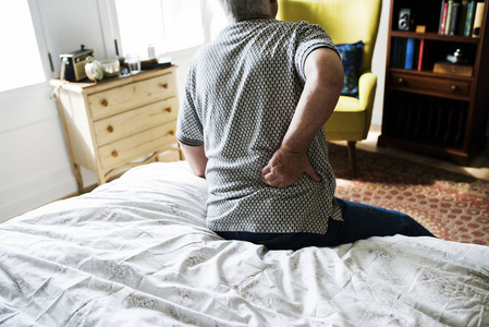 老人坐在床上,腰酸背痛照片