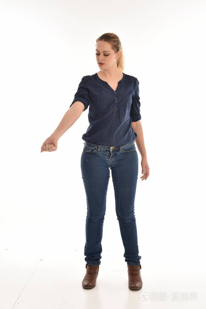 穿着简单的蓝色衬衫和牛仔裤站立姿势的女孩的全长肖像.