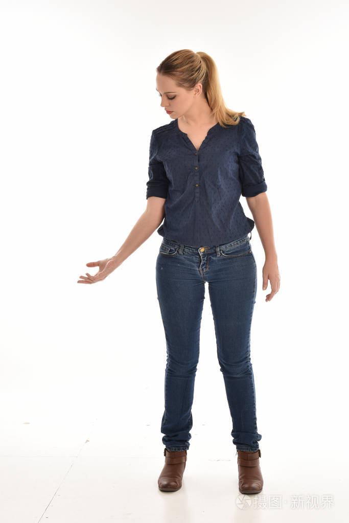 穿着简单的蓝色衬衫和牛仔裤站立姿势的女孩的全长肖像.