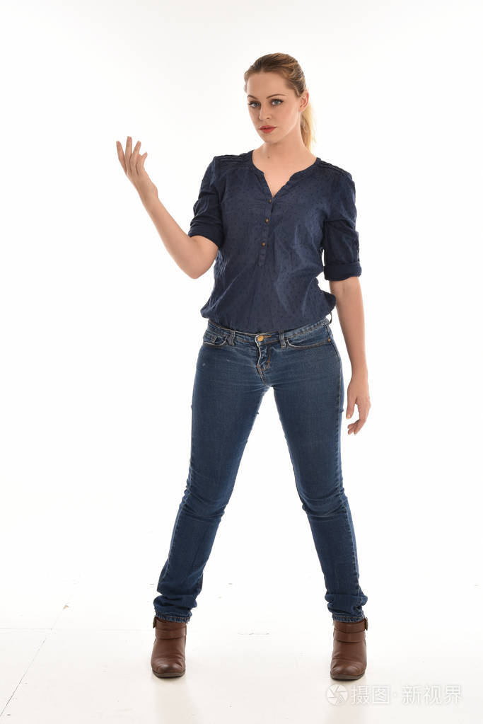 穿着简单的蓝色衬衫和牛仔裤站立姿势的女孩的全长肖像孤立在白色工作