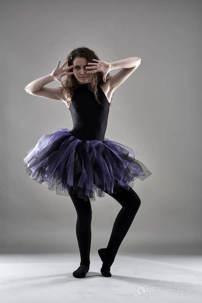 年轻女舞者在灰色背景下摆姿势