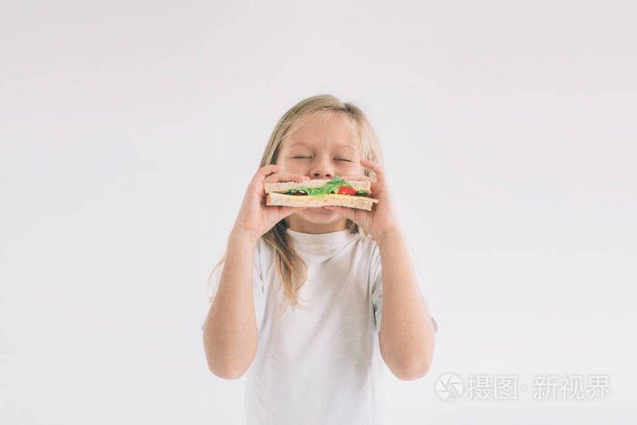 孩子拿着一块汉堡包孩子吃快餐不是有用的食物非常饿的婴儿女孩在白色