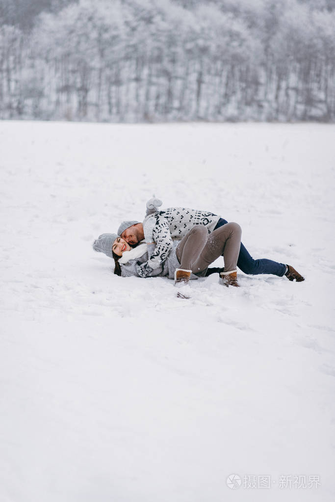 浪漫的一对情侣在冬天公园的雪地上拥抱