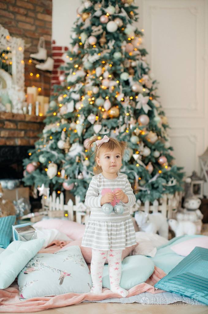 美丽的小女孩在圣诞树旁