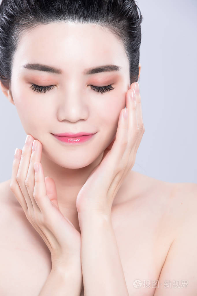 女人闭上眼睛触摸脸在灰色背景上有美容护肤的概念