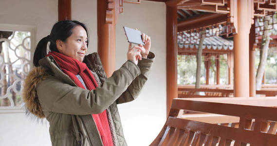亚洲妇女参观中国花园，用手机拍照和录像