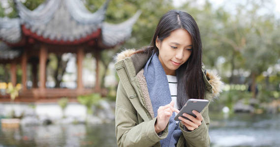 中国亭园APP上使用手机发送短信回复群聊的年轻女性