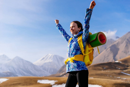 愉快的活跃女孩通过高加索山旅行, 举起她的手, 享受太阳