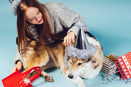 妇女在假日盖帽坐与狗在礼物背景