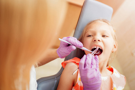 美丽的小女孩在牙医办公室参观。 她坐在椅子上，牙医在她身上擦亮了牙齿。