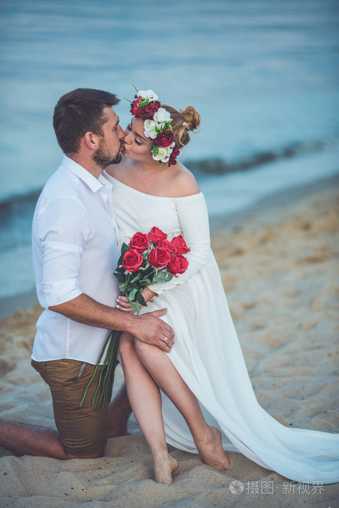 年轻的帅哥和他怀孕的妻子在河滩接吻