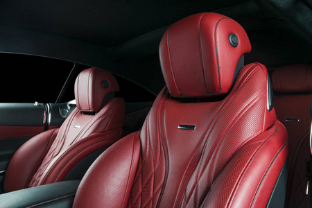 里面有现代豪华车。 豪华现代汽车的内部。 舒适的皮革红色座椅。 红色穿孔皮革驾驶舱与孤立的黑色背景。 现代汽车内饰细节