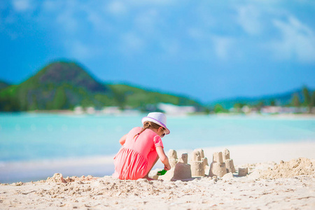小可爱的女孩在热带海滩做沙子城堡