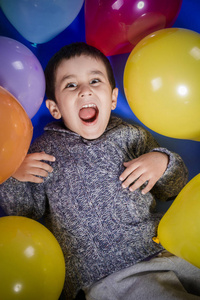 布鲁内特男孩在玩五颜六色的气球，在生日聚会上微笑和快乐