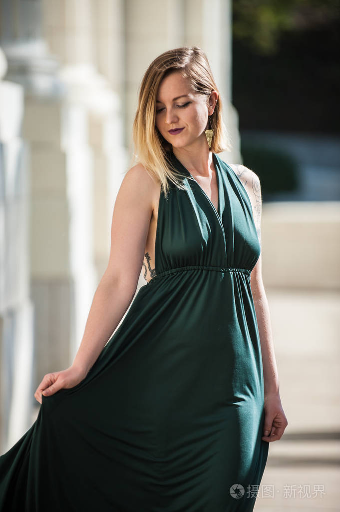 翡翠绿色吊带上衣看起来很漂亮在梦幻般的金发模特在混凝土步行