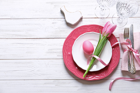 美丽的节日复活节餐桌，木制背景上有彩蛋和郁金香