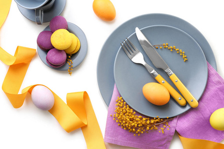 美丽的节日复活节餐桌设置含羞草和彩绘鸡蛋白色背景
