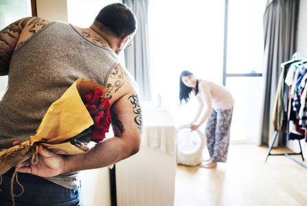 一对夫妇在洗衣服，男人用花束给女人惊喜
